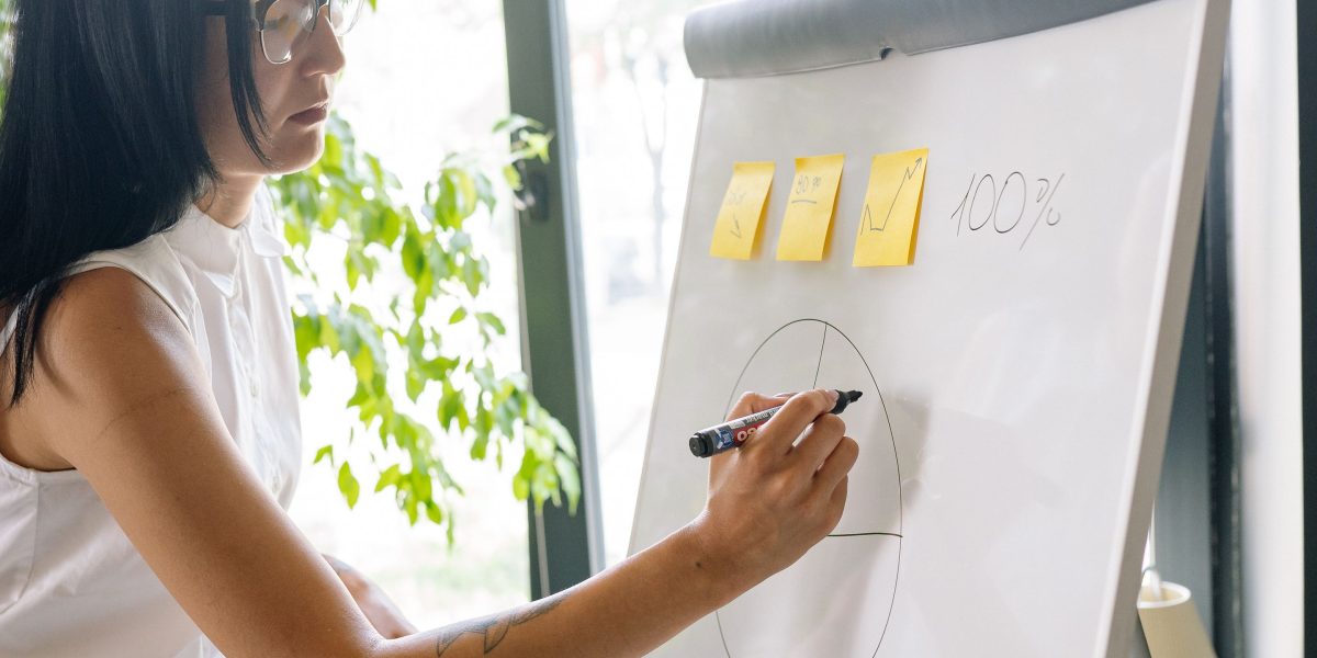 A person sketching ideas or writing on a whiteboard, symbolizing the strategic planning involved in structuring a portfolio for effective lead generation.