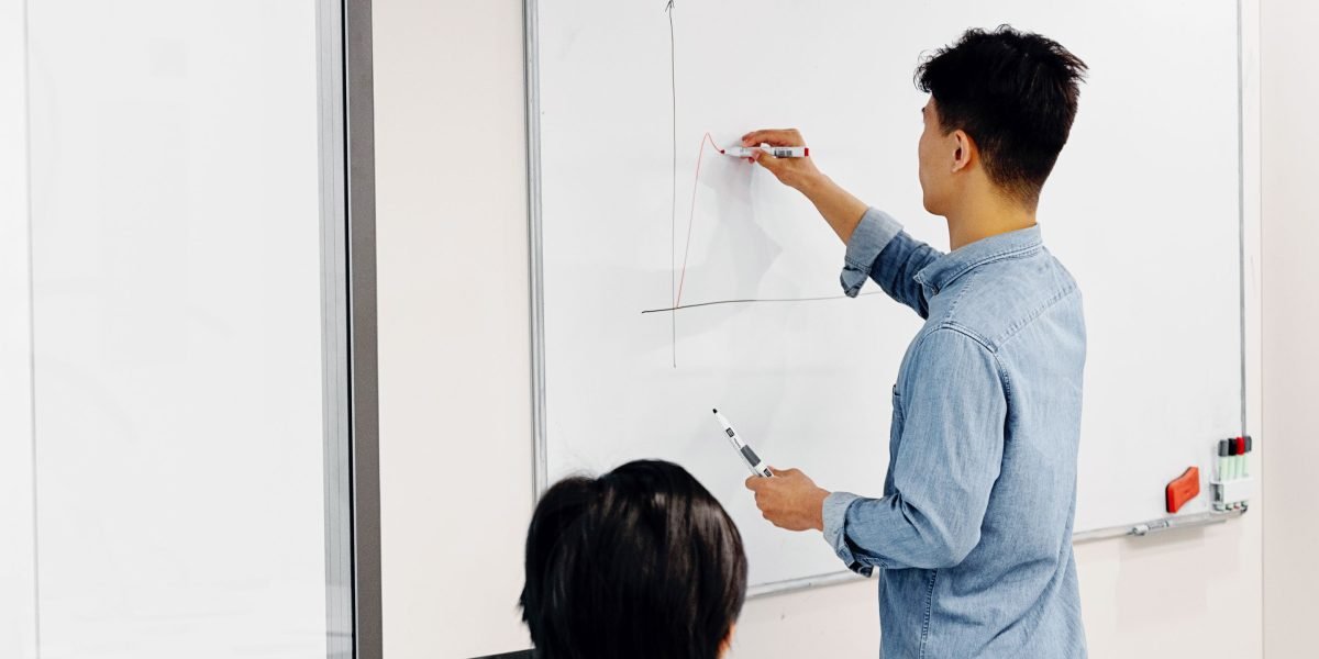 A person confidently outlines a strategic plan on a whiteboard, visualizing steps to achieve consistent lead generation for a business.