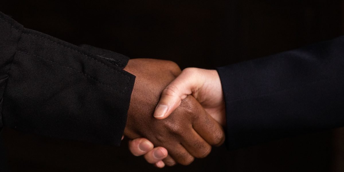 Two business professionals smiling and shaking hands, symbolizing a successful partnership agreement and the start of a collaboration.