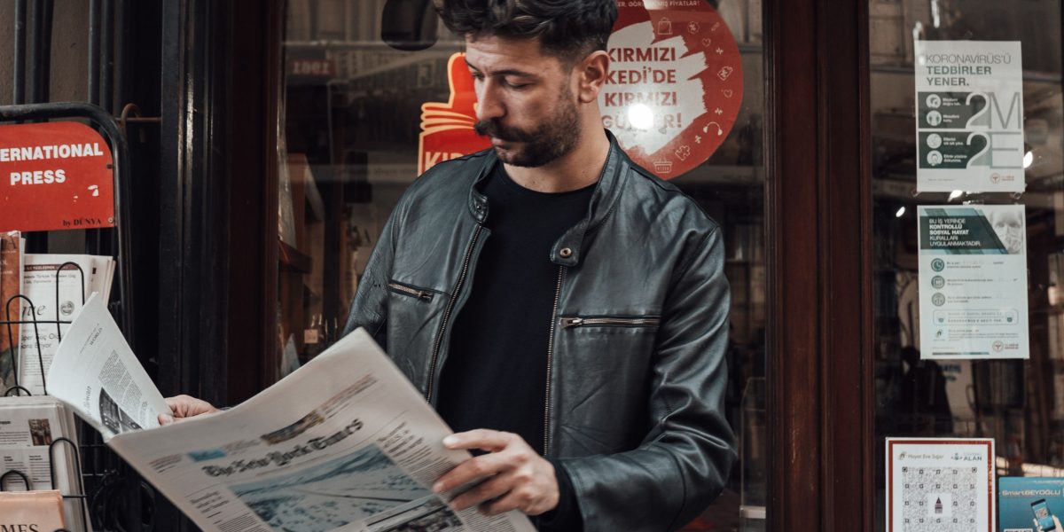 A person engrossed in reading a newspaper, highlighting the enduring impact of good design on reader engagement.